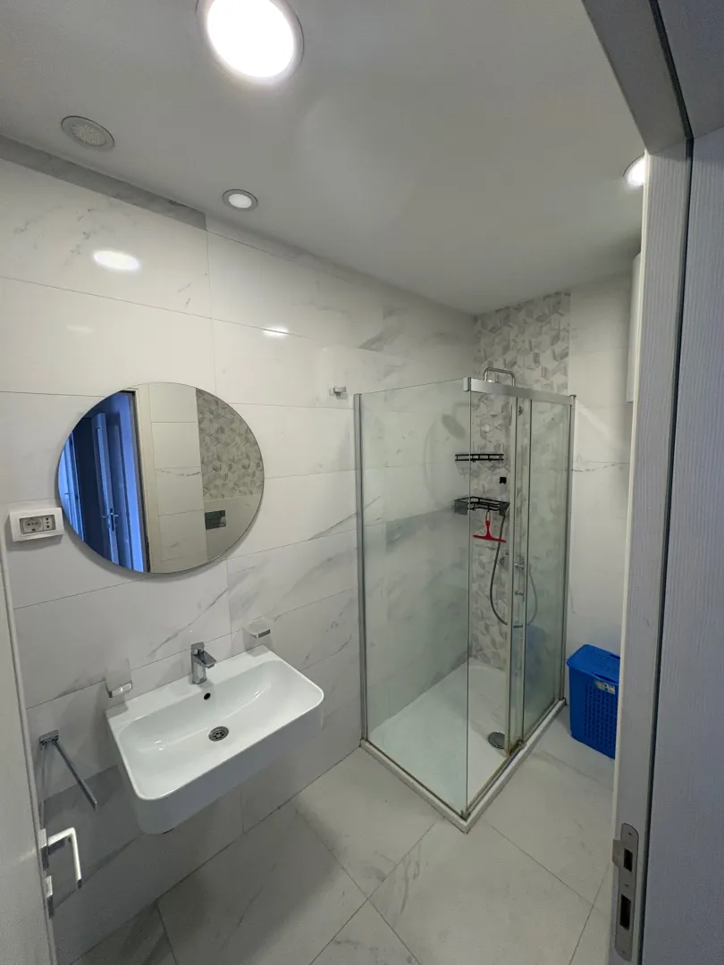 Modern bathroom equipped with a walk-in shower and washbasin.