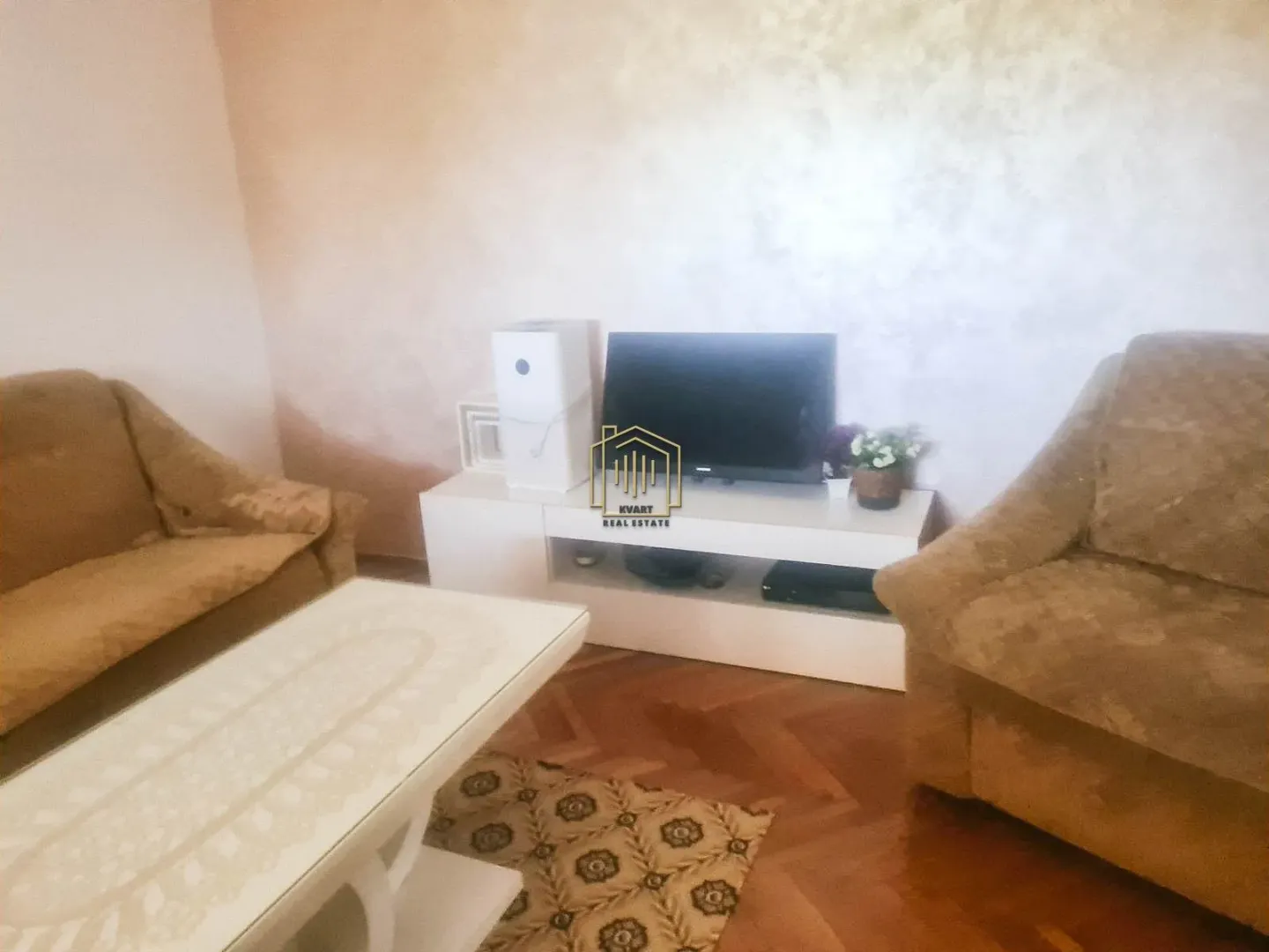 Dnevna soba sa garniturom, televizorom i stočićem.