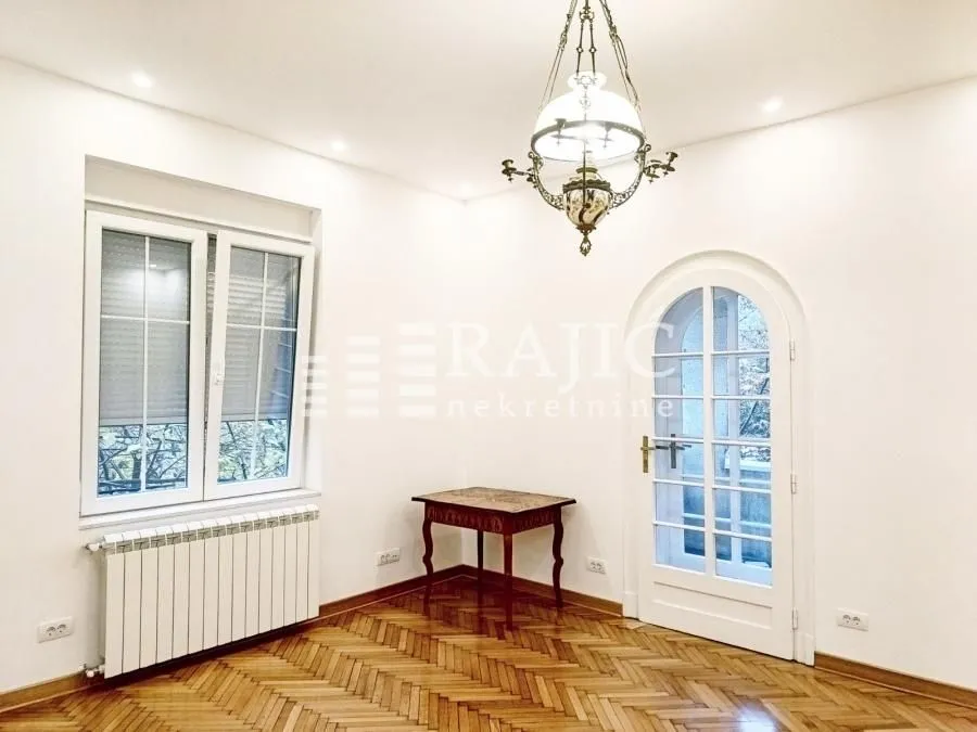 Empty room with parquet flooring, white walls, and a decorative chandelier.