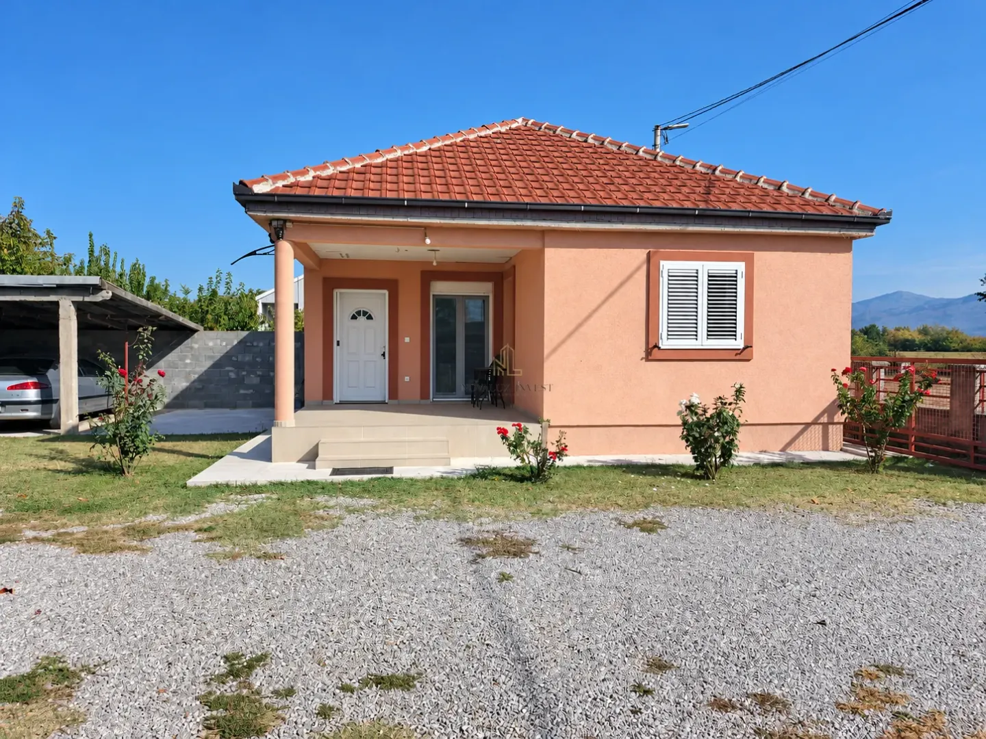 View of the front of the house with a covered terrace, yard, and parking area.