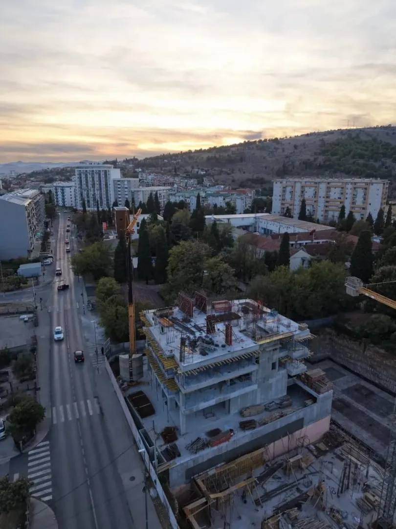 Pogled iz vazduha na gradilište stambene zgrade i okolnu ulicu.