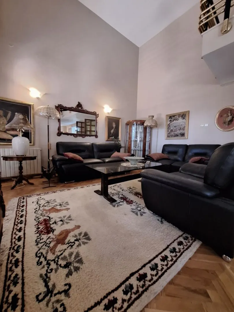 Spacious living room with black leather sofas and a high ceiling.