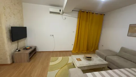 Living room with a sofa, TV, and yellow curtains. - image 2