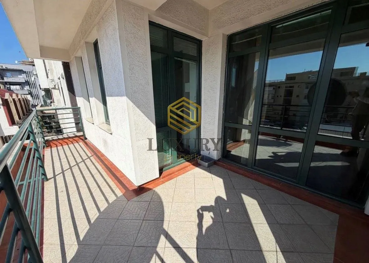 Prostrana prohodna terasa sa pločicama i metalnom ogradom.