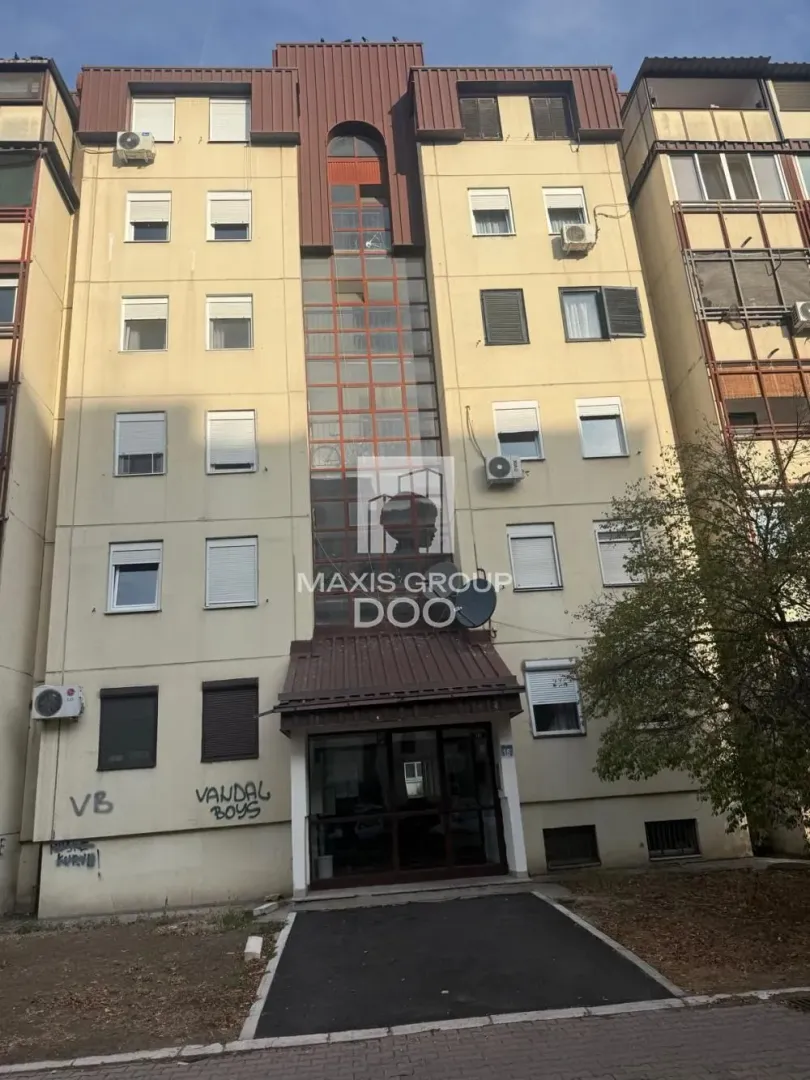 Prednji pogled na višespratnu stambenu zgradu sa ulazom.