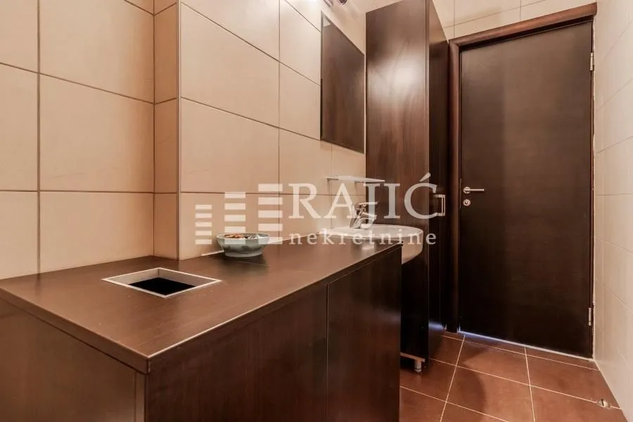 View of the bathroom with dark furniture and ceramic tiles.