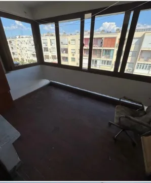 Enclosed balcony with a view of neighboring buildings. - image 5