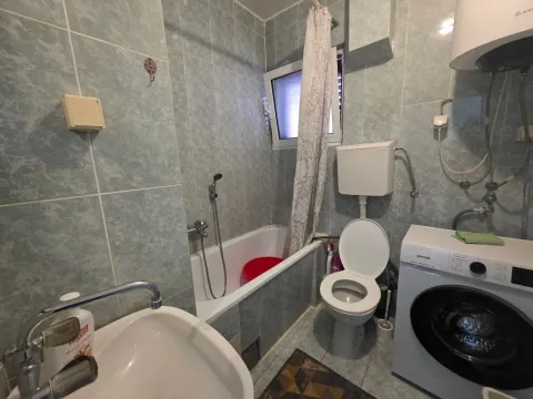 Smaller tiled bathroom with a bathtub, toilet, and washing machine. - image 14