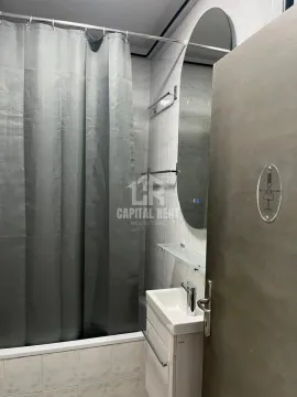 Smaller bathroom with a bathtub, grey curtain, washbasin, and mirror. - image 14