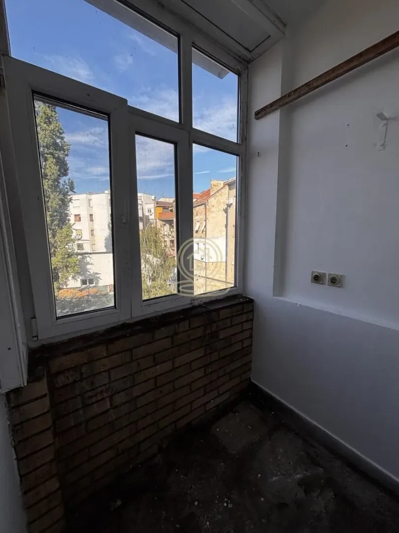 Zastakljeni balkon sa pogledom na okolne zgrade i gradsko naselje.