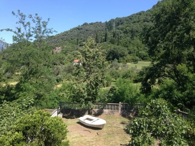 Dvorište okruženo zelenilom sa pogledom na brda.