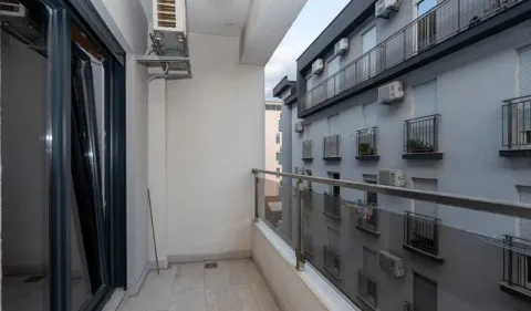 Nadtkriveni balkon sa staklenom ogradom i pogledom na susjednu zgradu. - image 8