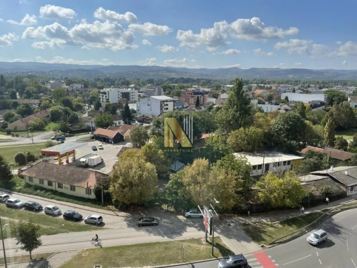 Pogled sa prozora na okolno naselje i zelenilo.