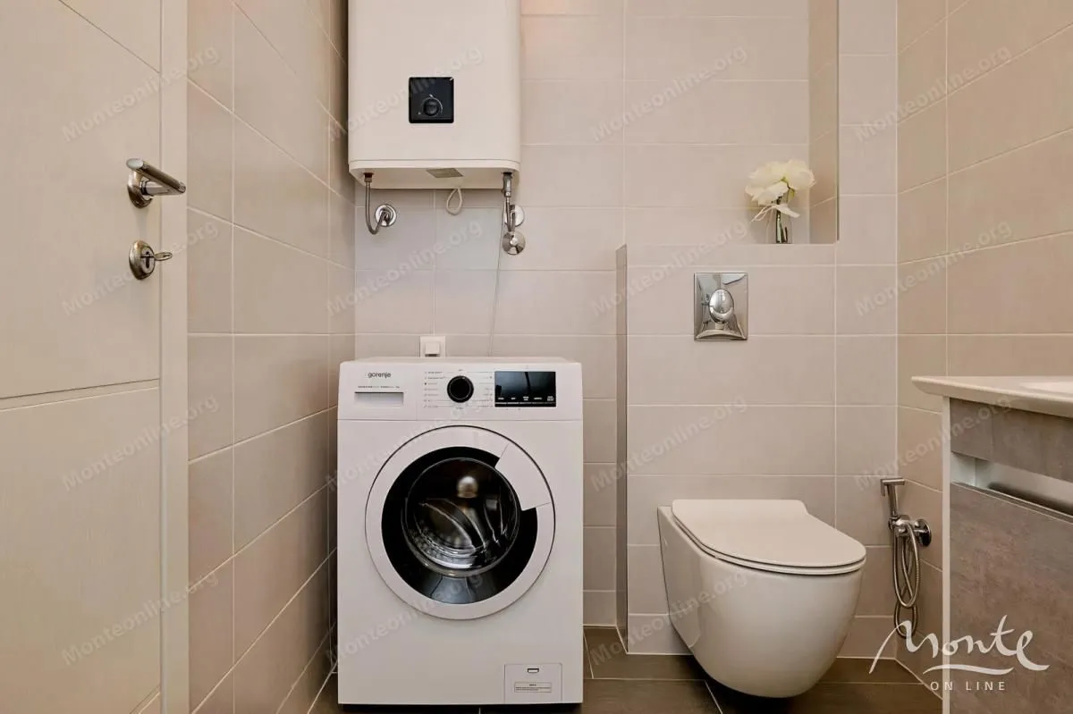 Kompaktno kupatilo sa tuš kabinom, WC šoljom, umivaonikom i veš mašinom.