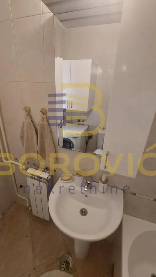 Manje kupatilo sa umivaonikom, ormarićem i mašinom za veš.