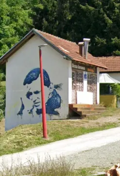 Exterior of a small commercial building with a mural on the wall next to the road. - image 4
