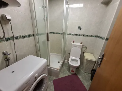 Smaller bathroom with a shower cabin, toilet, and washing machine. - image 7