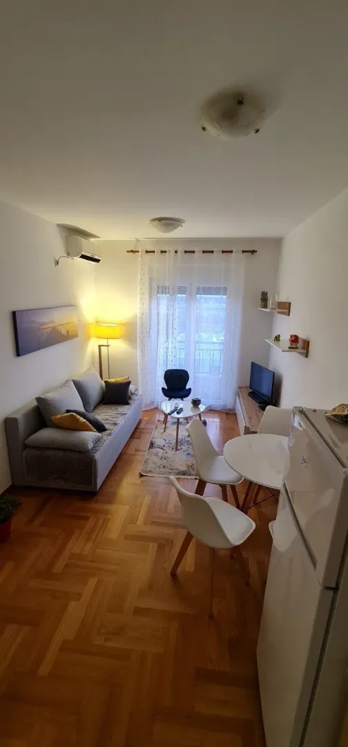 Svijetla dnevna soba sa trpezarijskim stolom i izlazom na balkon.