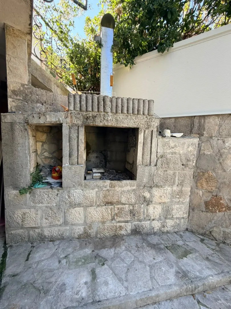 Kameni roštilj u dvorištu kućnog objekta.