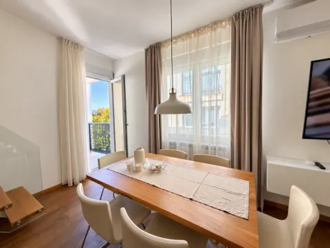 Dining area with a wooden table, white chairs, and access to the terrace. - image 18