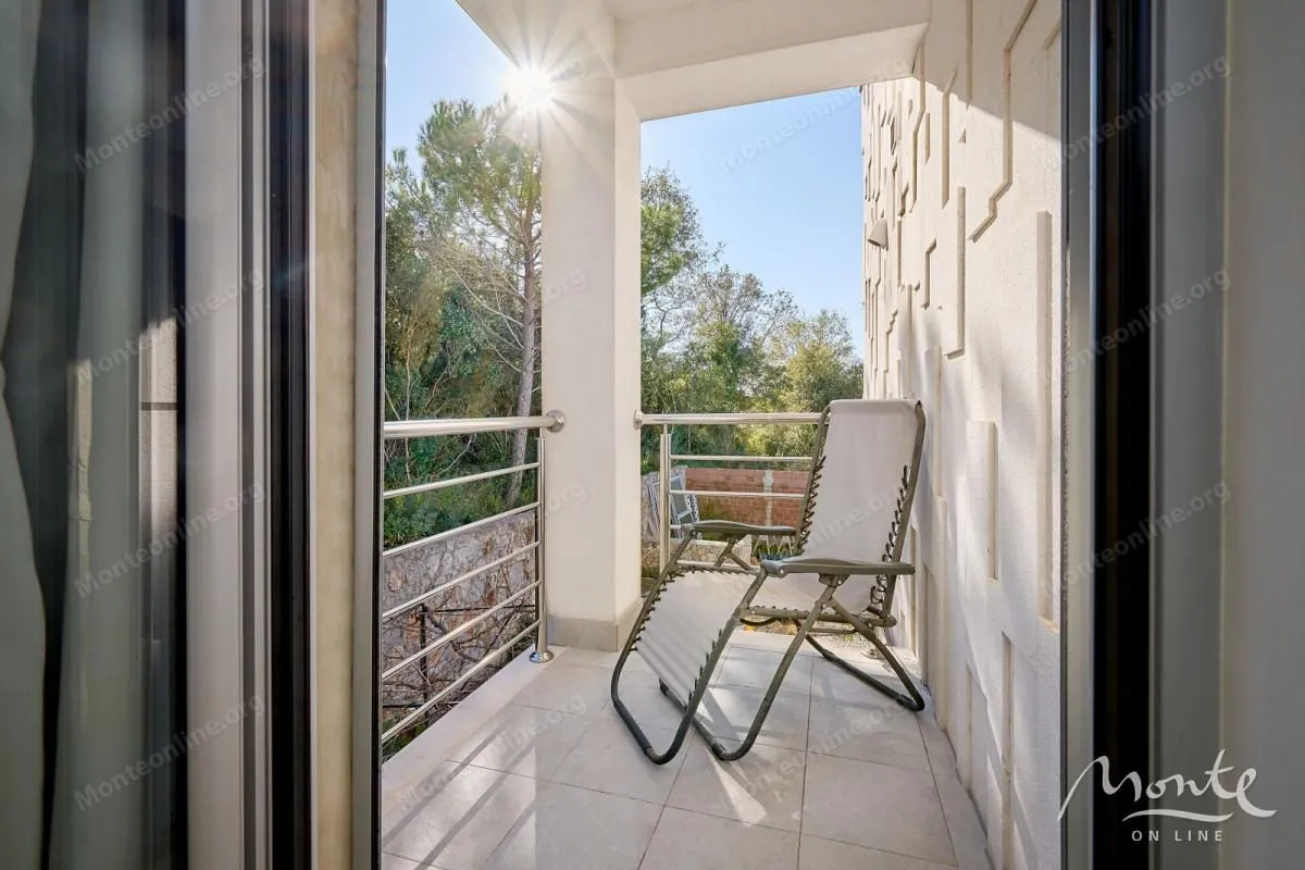 Natkriveni balkon sa metalnom ogradom i stolicom za odmor.