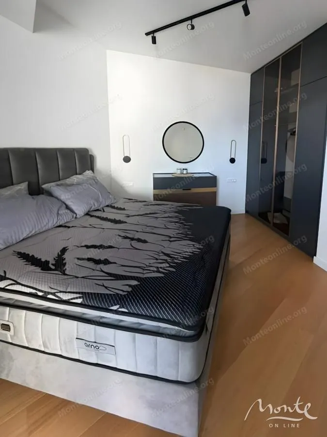 Moderna spavaća soba sa bračnim krevetom, garderoberom i komodom sa ogledalom.