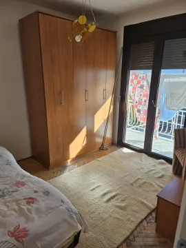 Spavaća soba sa velikim drvenim ormarom i izlazom na balkon. - image 5