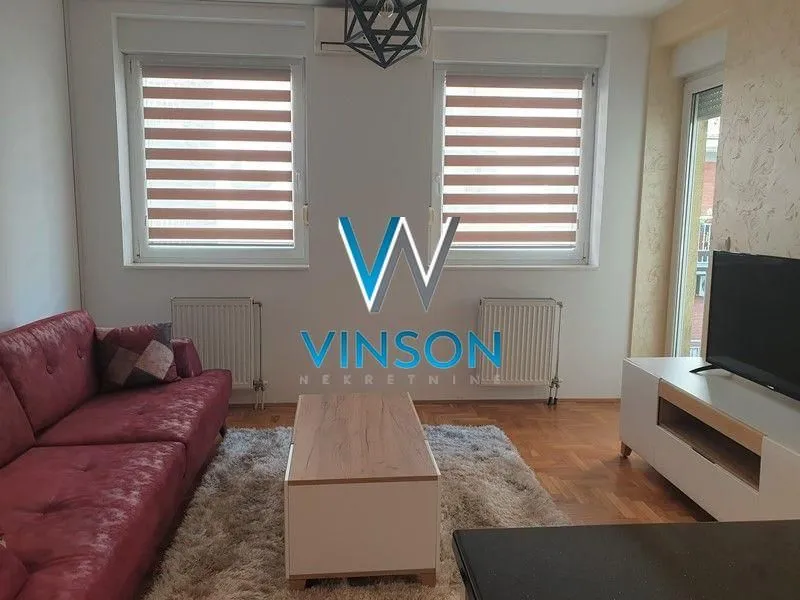 Dnevna soba sa crvenom garniturom, stočićem i televizorom.