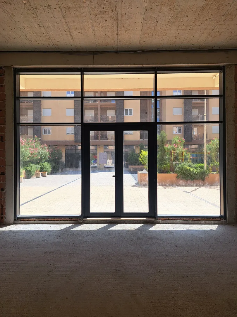 View through a large glass wall towards the courtyard and surrounding buildings in a new construction.
