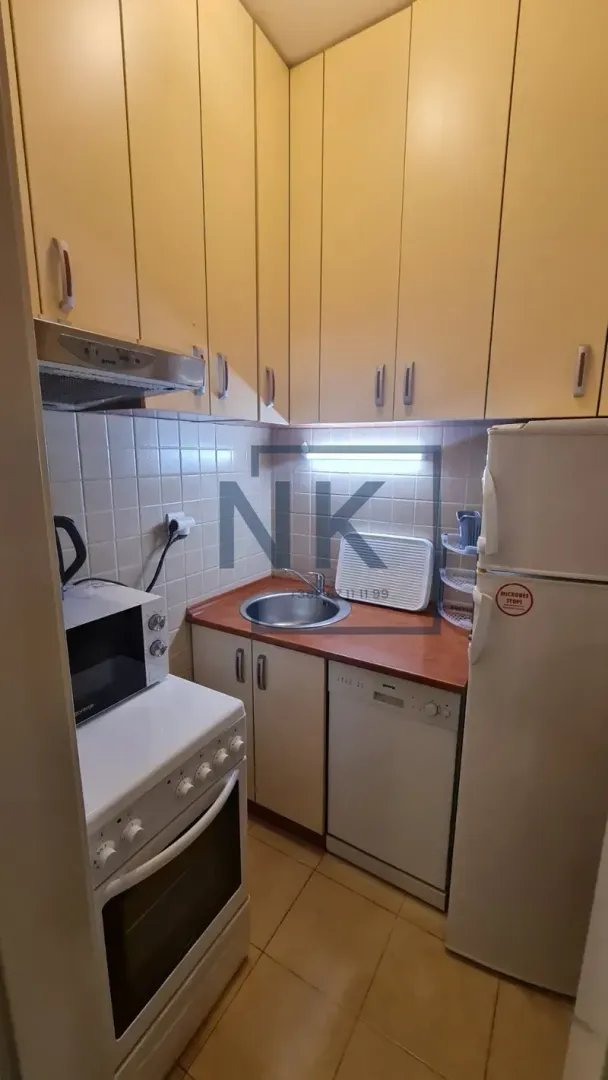 Compact kitchen with cabinetry, stove, refrigerator, and sink.