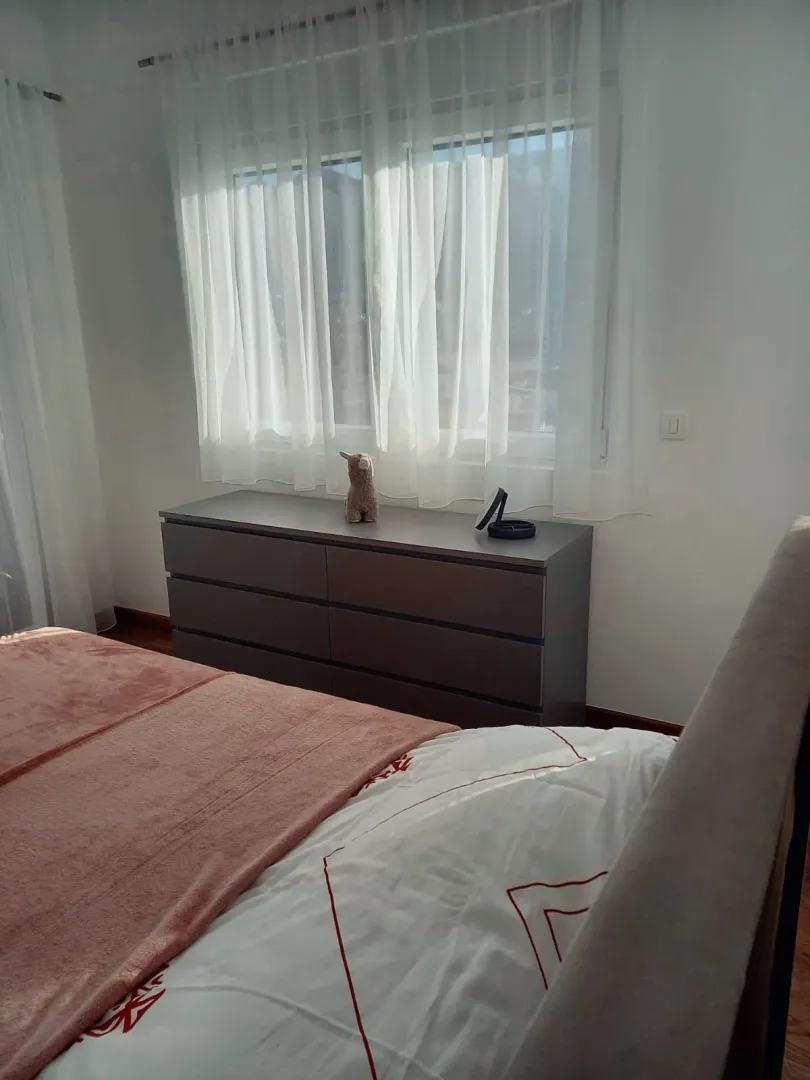 Bedroom with a double bed, chest of drawers, and a window with curtains.