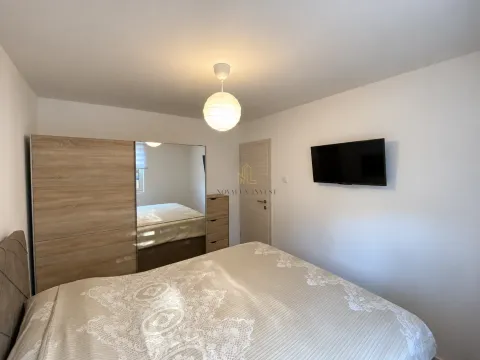 Furnished bedroom with a double bed, large wardrobe, and wall-mounted television. - image 13