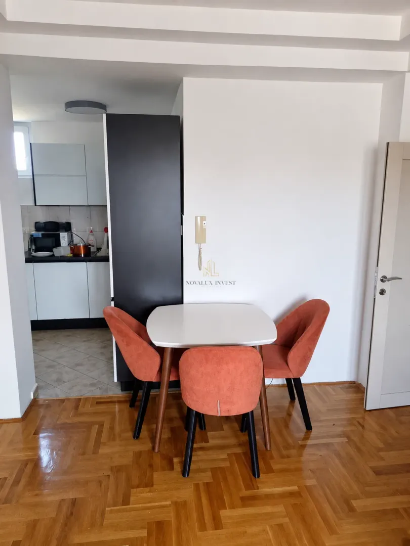 Trpezarijski sto sa narandžastim stolicama i pogledom na kuhinju.