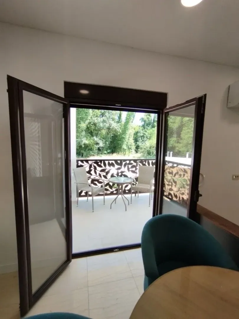 View from the room towards a furnished balcony with outdoor seating.