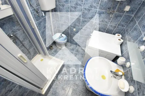 Smaller tiled bathroom equipped with a shower cabin, sink, and toilet. - image 11