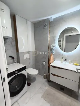 Savremeno opremljeno kupatilo sa umivaonikom, WC šoljom, veš mašinom i velikim ogledalom. - image 11