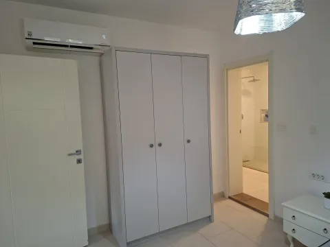 Svijetla spavaća soba sa ormarom, klima uređajem i pogledom na kupatilo. - image 9