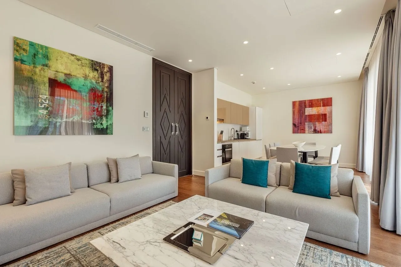Svijetla dnevna soba otvorenog tipa sa modernim namještajem i trpezarijom u pozadini.
