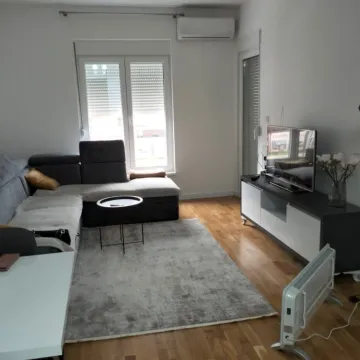 A bright living room featuring a corner sofa, television, and wooden flooring. - image 6