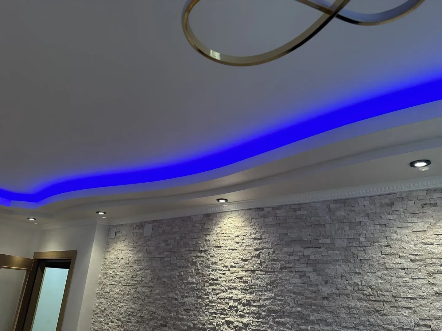 Detail of a modern interior featuring a decorative stone wall and LED ceiling lighting.