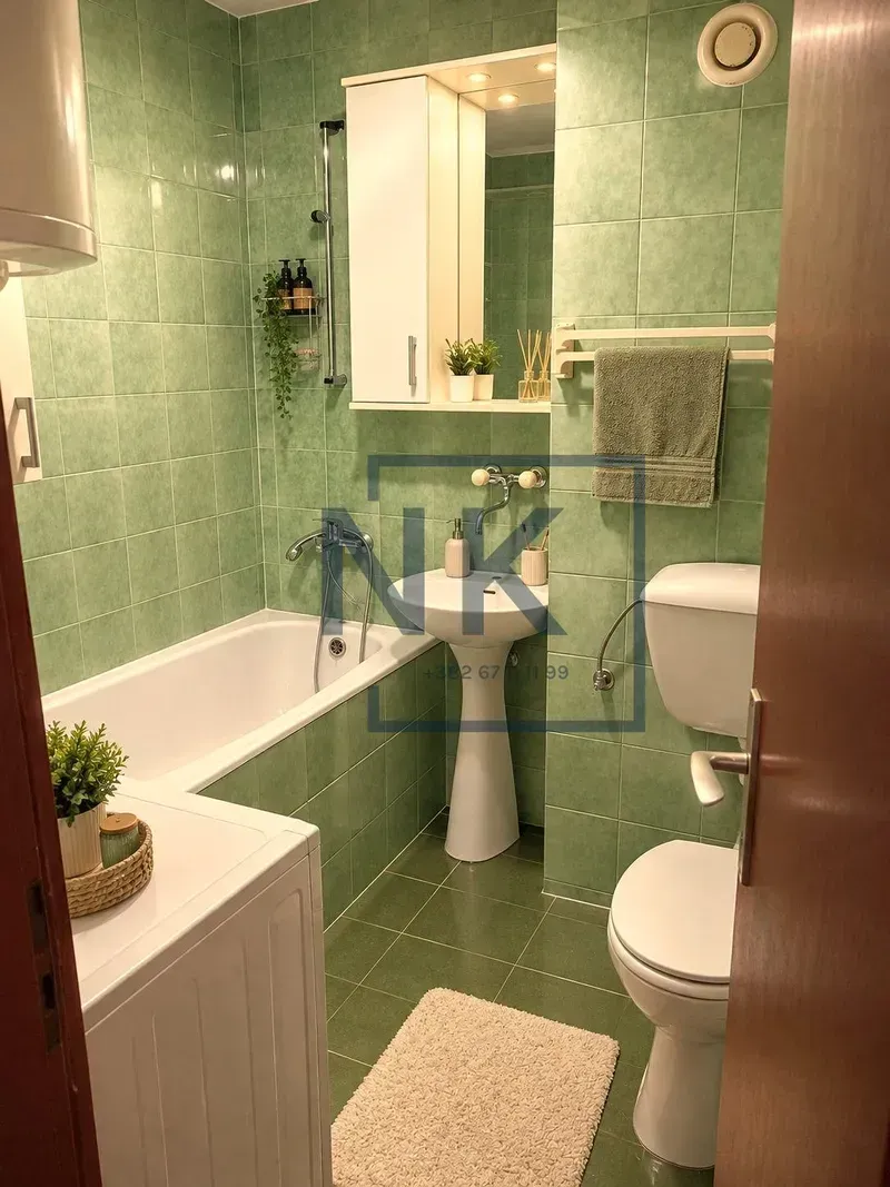 Kupatilo obloženo zelenim pločicama sa kadom, umivaonikom i toaletom.