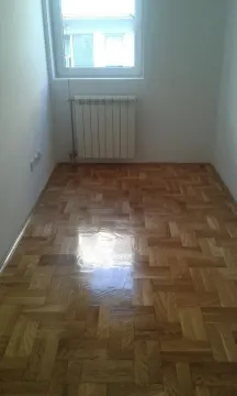 Prazna soba sa parketom i radijatorom ispod prozora. - image 5
