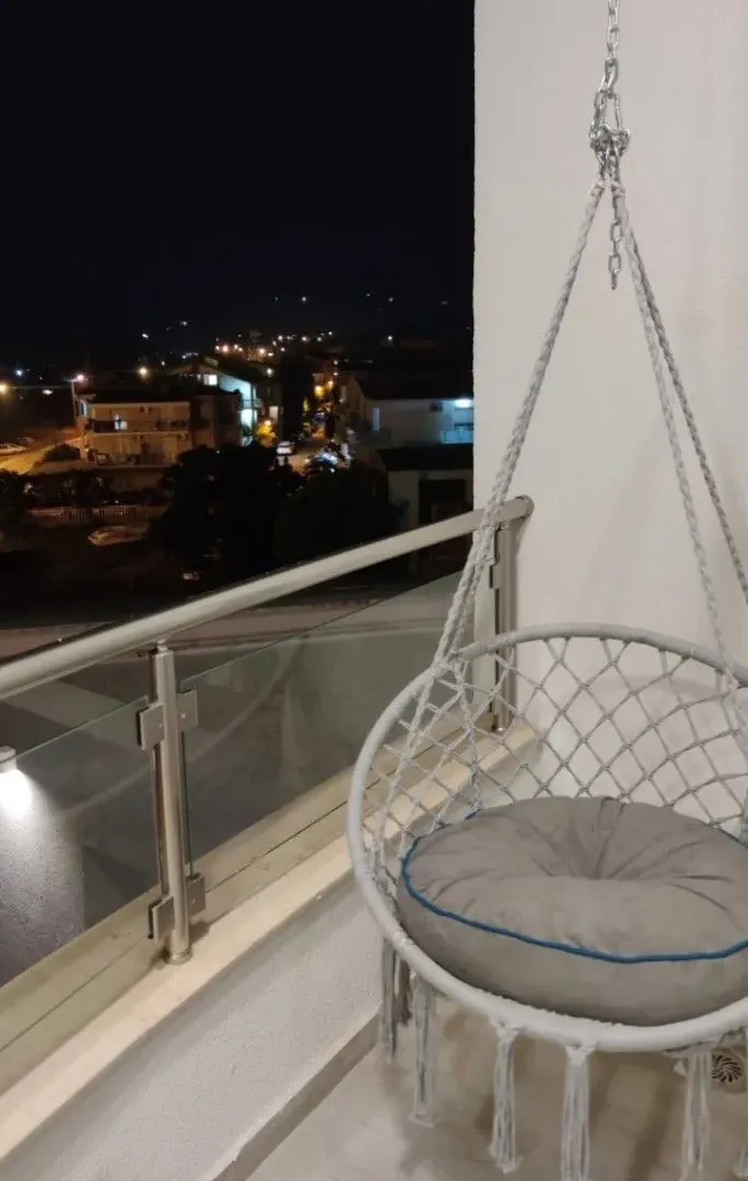 Furnished balcony with a hanging chair and a night view.