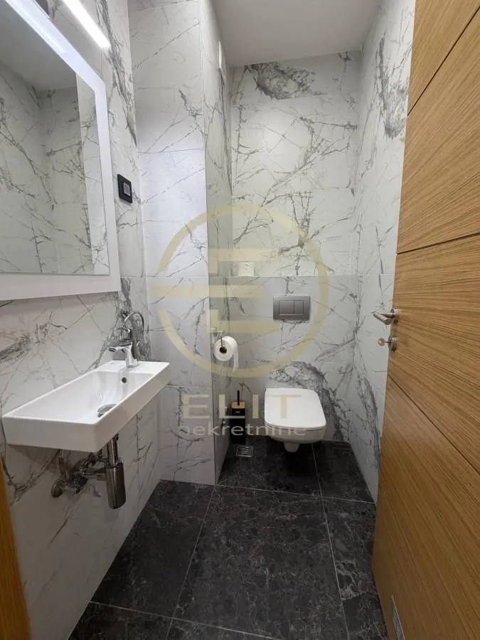 Modern bathroom equipped with a washbasin, toilet, and marble tiles.