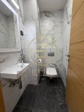 Modern bathroom equipped with a washbasin, toilet, and marble tiles. - image 17