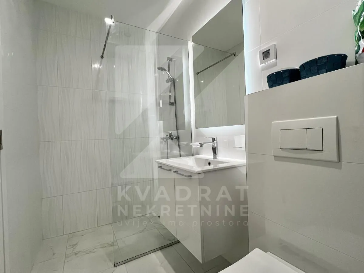 A modernly equipped bathroom with a walk-in shower and a washbasin.