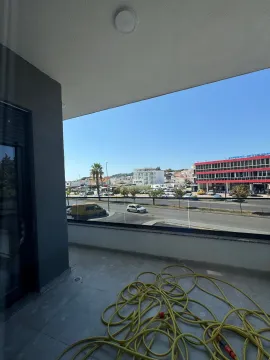 Nenamješten balkon sa staklenom ogradom i pogledom na ulicu i okolne zgrade. - image 6