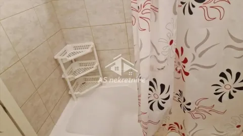 View of the bathtub with a curtain and shelves in the bathroom. - image 15