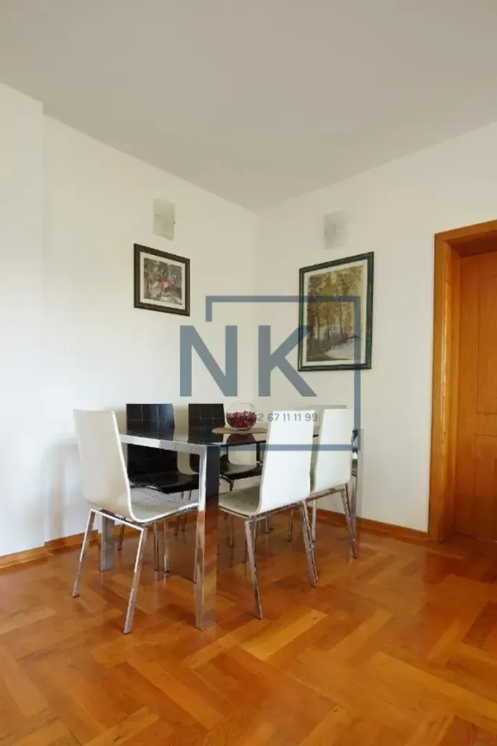 Dining area with a table, chairs, and parquet flooring.