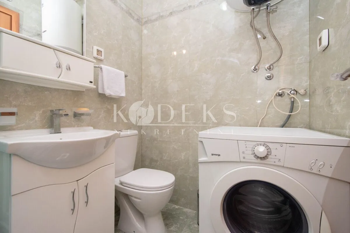Compact bathroom with a washbasin, toilet, and washing machine.